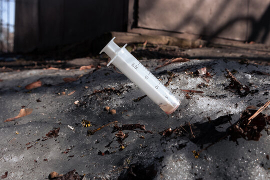 Used syringe sticks out in the dirty snow. A real syringe used by a drug addict