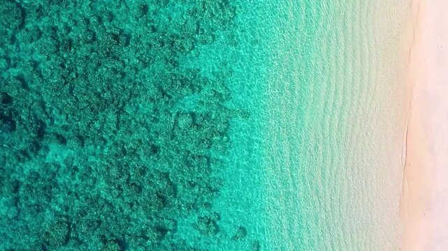 Aerial drone view of calm turquoise waves and a sandy tropical beach. Top view of a serene secluded cove and soft ocean surf. Concept of relaxation, summer vacation and peaceful nature.