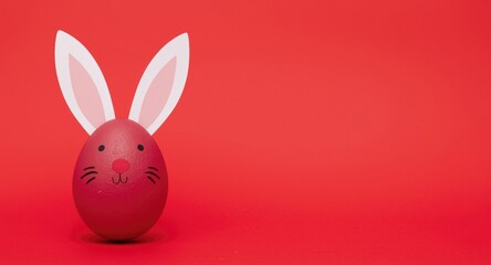 Obraz premium Handmade paper bunny ears on a crimson Easter egg set on a bright red background