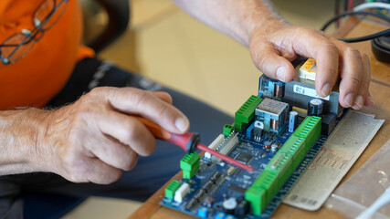 Professional technician analyzing printed circuit boards under bright lights in testing lab