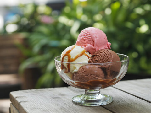 Delicious ice cream scoops in a glass bowl on a rustic table