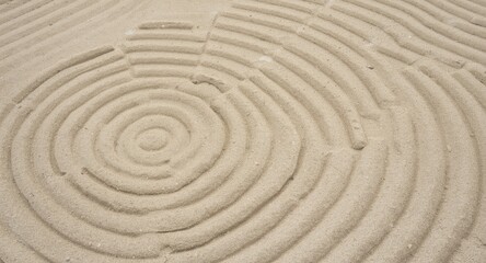 Fototapeta premium Meditative Zen Garden sandscape with circular raked patterns seen from an overhead angle