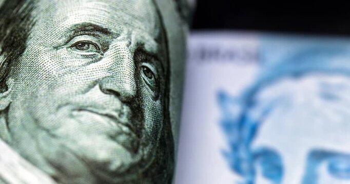 Detail video of a Brazilian one-hundred-real note, next to one-hundred American dollar notes. Economic crisis and rise in the American currency, rise or fall of the dollar in reference to the Brazilia