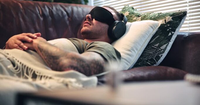 Psychedelic, appointment and man with headphones on sofa, blindfold therapy or soldier with eye mask. Mental health, counseling and person with military trauma on couch, audio and sensory deprivation