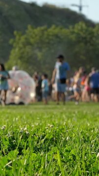 Zorbing at a Summer Festival, blurred silhouettes of a happy crowd enjoying the park