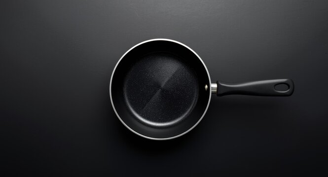 Overhead perspective of empty saucepan featuring nonstick Teflon coating on black backdrop