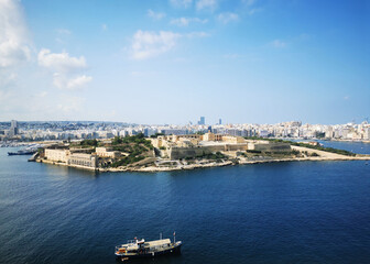 Obraz premium Island fortress of Malta surrounded by calm blue sea under clear sky. The image conveys the concept of coastal heritage and wide Mediterranean landscape.