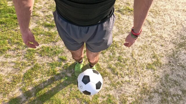 First person view of a skilled football player juggling and performing a trick with a soccer ball on a grass field in slow motion