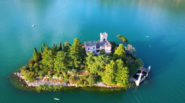 Italy Lake Iseo Loreto Island aerial drone reveal. Medieval style castle on tiny island in Lombardy. Cinematic crane shot rising up above turquoise water of Iseo lake Alps travel scenery 4k