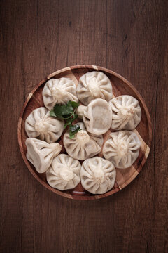 khinkali, on a wooden plate, Georgian traditional dish, on a wooden table, no people,