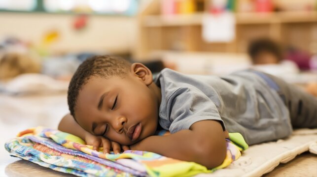 A small child peacefully sleeps on a colorful pillow during preschool nap time. Soft daylight fills the cozy classroom, creating a gentle, serene atmosphere.
