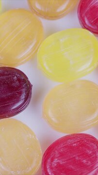 Vivid candy display. Multicolored spherical sweets arranged on plain backdrop for display. Assorted vibrant candies spread across white background with glossy sugar coating