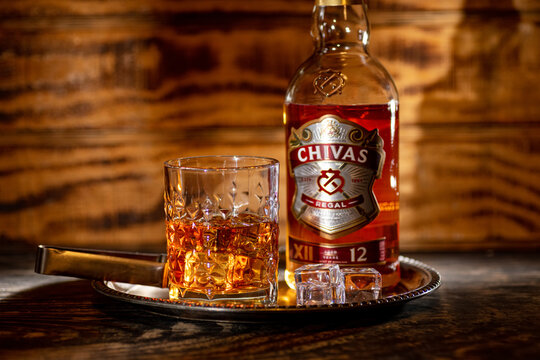 Chivas Regal whiskey bottle with glass of scotch whisky and ice on tray