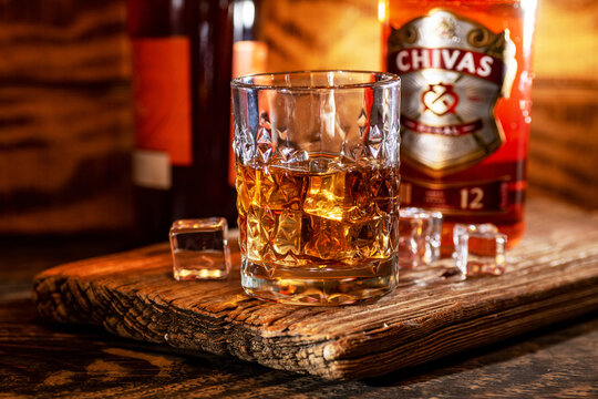 Close up of Chivas Regal whiskey glass with ice cubes on wooden background