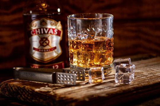 Premium Chivas Regal scotch whisky with glass and ice cubes in bar setting
