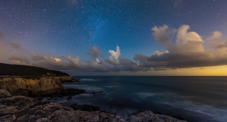 Fototapeta premium Serene night view of a summer coast with sparkling stars and ocean clouds