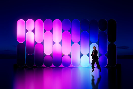 Asian woman jumping in front of glowing 3D abstract light panels installation at night