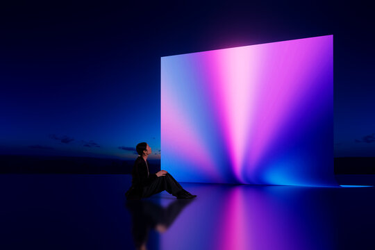 Asian woman sitting and looking at glowing 3D gradient light wall in dark environment