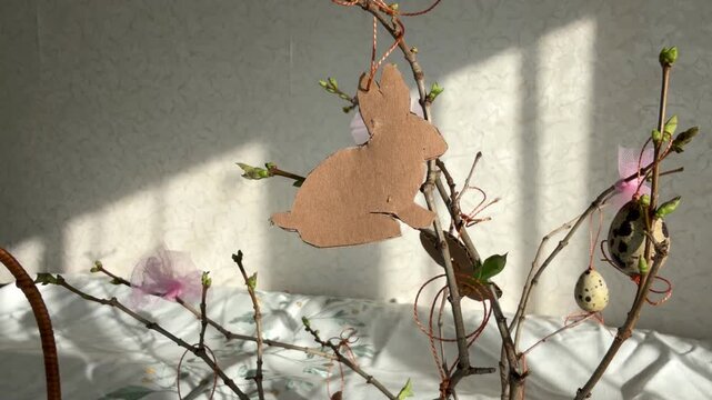 Step by step instructions: Close up of a handmade cardboard bunny hanging on an Easter branch. Spring morning atmosphere.