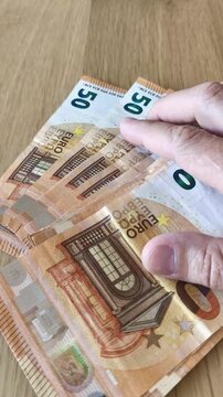 Dedos contando billetes de 50 euros, rutina aburrida de dinero y finanzas
