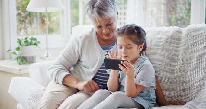 Grandmother, girl and phone with video call, wave goodbye and bonding together for weekend in house. Happy, old woman and grandchild in lounge with tech, contact and blow kiss for virtual connection.