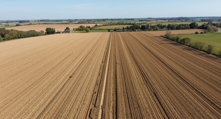 Fototapeta premium Extensive farm fields showing earth preparation and rural land use under clear skies