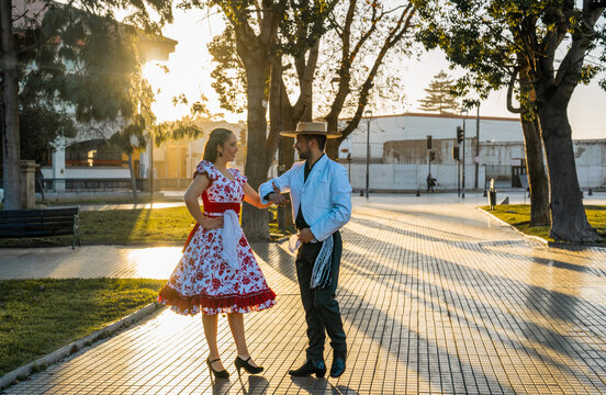 Chilean man and woman in traditional huaso and china costumes performing national dance