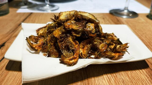 Fried artichokes on a plate, a classic dish of Italian and Spanish cuisine, known for their delicate flavor with nutty notes and crispy texture. High quality 4k footage