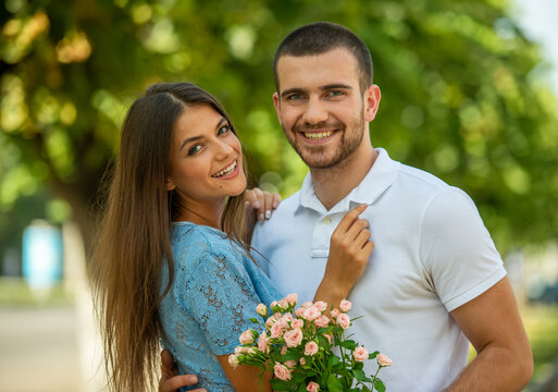 Happy couple hugging with flowers outdoors.