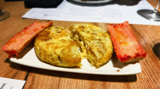 Pan con tomate and tortilla served on a plate in a cozy restaurant. Concept of spanish cuisine. High quality 4k footage