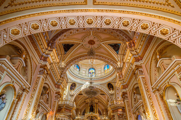 Obraz premium Ornate pink and gold arched ceiling with geometric patterns and stained glass dome inside Sanctuary of Nuestra Señora de los Remedios in Cholula, Puebla, Mexico