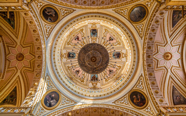 Obraz premium Symmetrical view of ornate pink and gold dome ceiling with massive central chandelier and painted medallions of Franciscan saints inside Sanctuary of Nuestra Señora de los Remedios in Cholula, Mexico