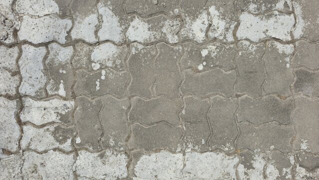 Old and worn-out interlocking concrete paver background. Grungy concrete pavement with aged texture and white staining. Detailed view of interlocking pavers with natural wear and weathering.
