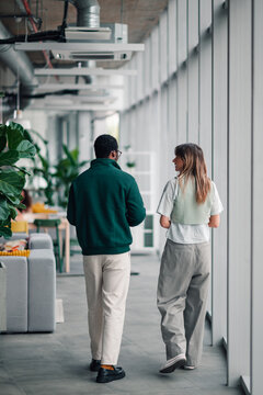 Diverse coworkers walking and talking in office hallway