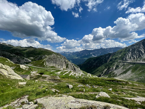 winding mountain road curves dramatically through rugged terrain, cutting across steep cliffs and lush valleys. sweeping landscape, travel, grandeur of alpine scenery.