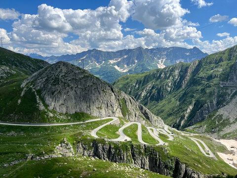 winding mountain road curves dramatically through rugged terrain, cutting across steep cliffs and lush valleys. sweeping landscape, travel, grandeur of alpine scenery.