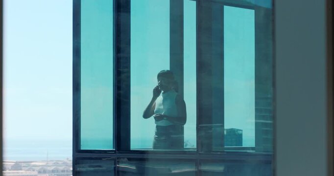 Window, speaking and woman with phone call in office, consulting client and stocks investment discussion. Negotiation, feedback or investor with mobile for economic update, planning or trading advice