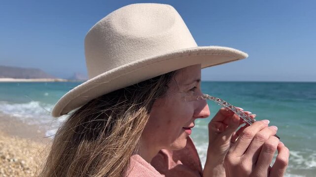 Primer plano mujer perfil quit&aacute;ndose gafas para mirar el mar