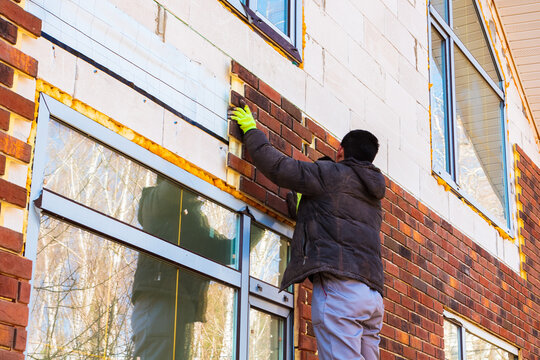 A man works with a drill, attaches thermal panels made of clinker