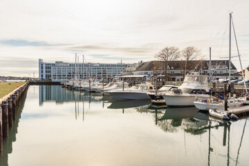 Luxury yachts in a harbour under partly cloudy sky on fall morning. Reflection in water.