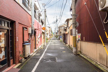 Narrow street with a cycle lane lined with residential buildings in a city centre. Kyoto, Japan.