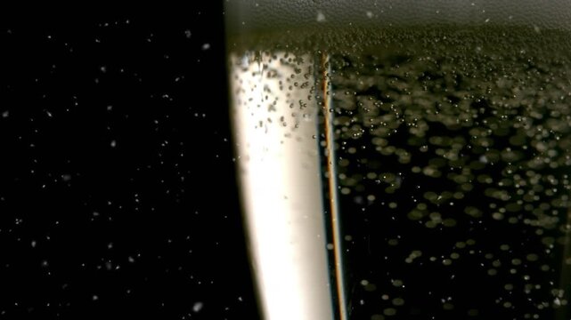 Animation of snow falling over glass of champagne