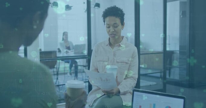 Animation of network of digita icons over two diverse women discussing over a document at office