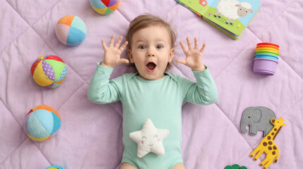 Naklejka premium Surprised baby lying on a purple blanket surrounded by toys