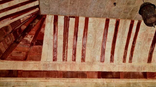 Showing the interior arch ceiling of Amer Fort with red sandstone and marble inlay patterns, curved ribs, and carved stone brackets highlighting traditional Rajput�Mughal architecture.