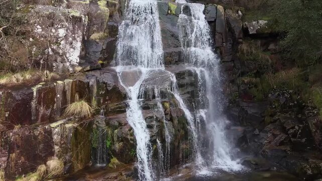 Water rushing down a multi-tiered rock formation into a calm pool in a natural landscape