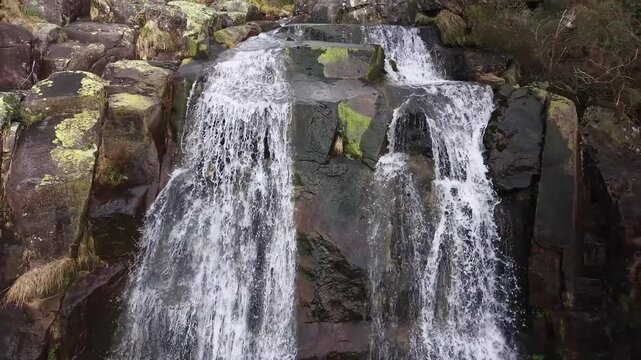Water rushing down a multi-tiered rock formation into a calm pool in a natural landscape