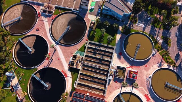 Dirty water in the round reservoirs at water recycling plant. Drone footage over the modern waterworks on sunny day.