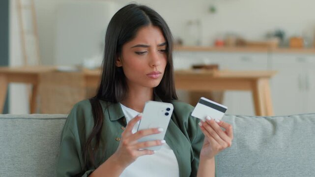 Serious confused Indian woman trying pay online transaction error entering bank credit card at home frustrated stressed Arabian female girl mobile phone blocked account shopping failure problem indoor