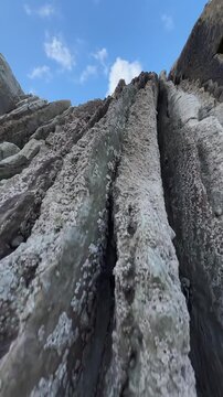 Close-up of layered coastal rock formation from below in Sopelano